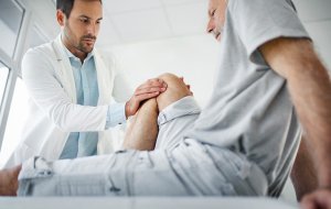 Lekarz bada kolano pacjenta